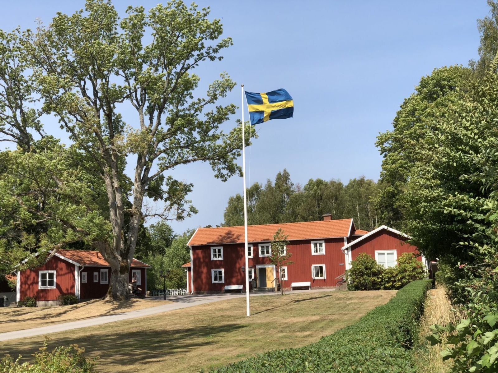 Röda hus och en svensk flagga i en hög flaggstång. 